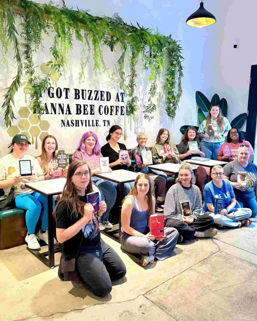 A book club meeting holds up their favorite books at an event for The Bookshop Nashville