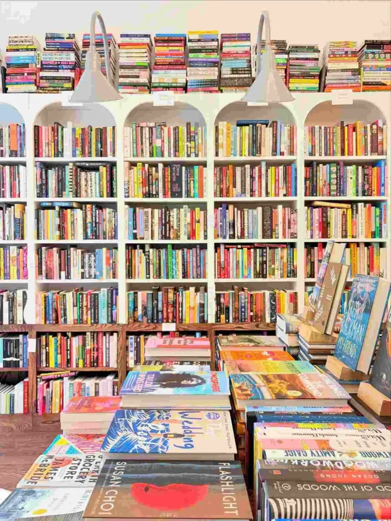 A curated display of new releases sits before white arched bookshelves at The Bookshop Nashville