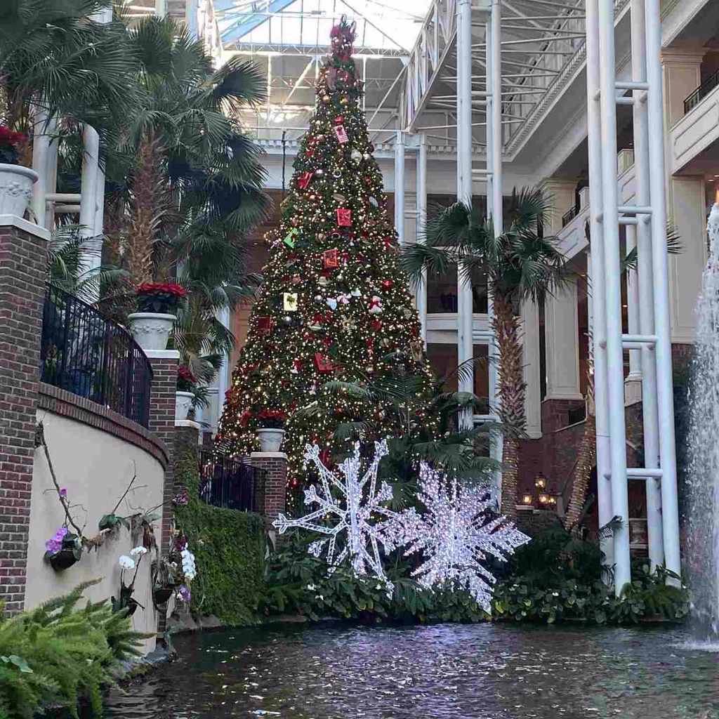 A giant, decorated Christmas tree stands in a grand atrium with palm trees and a fountain, capturing the festive spirit of Nashville in November.