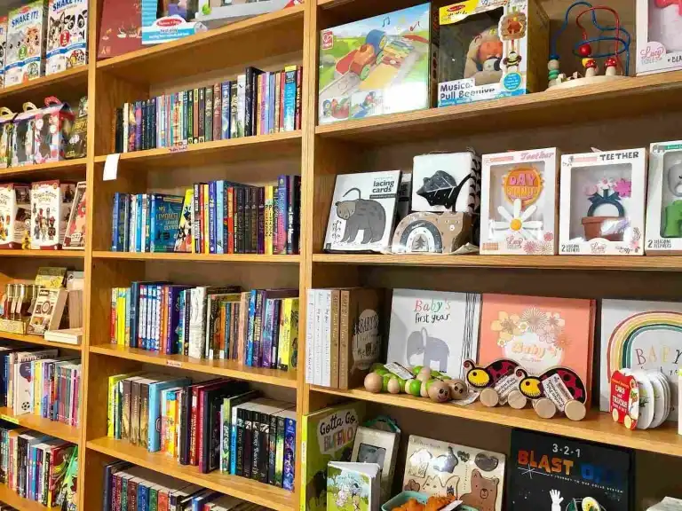 Wooden shelves filled with children's books and educational toys inside Fairytales Bookstore Nashville
