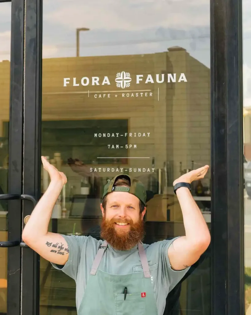 The smiling owner of Flora and Fauna Nashville stands outside the cafe holding his arms up