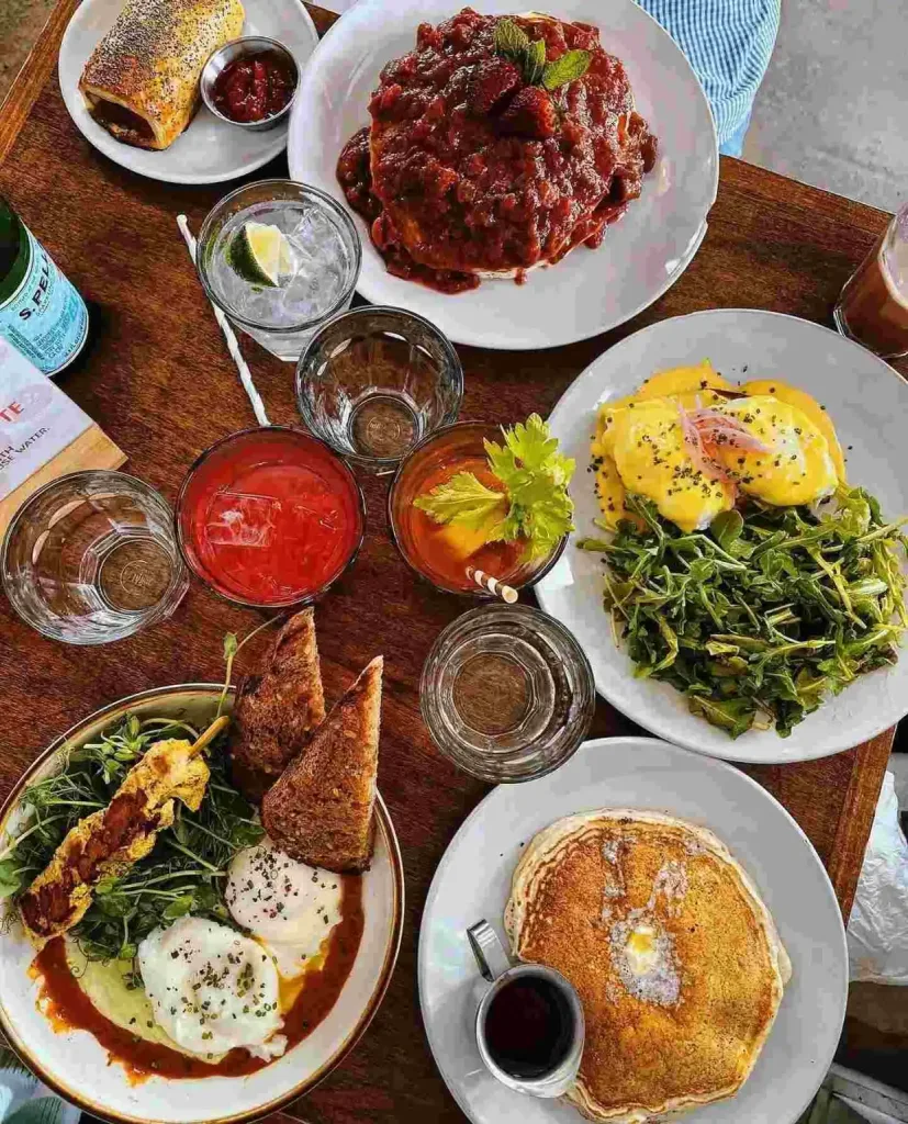 A table spread of brunch items, including pancakes and eggs benedict, highlighting the menu at Hearts Nashville.
