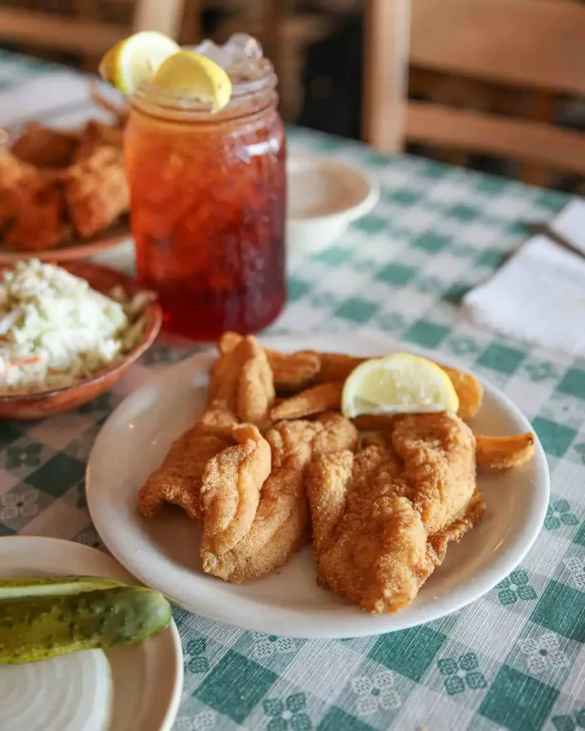 A plate of fried catfish and a drink on a green checkered tablecloth at Uncle Bud's Nashville
