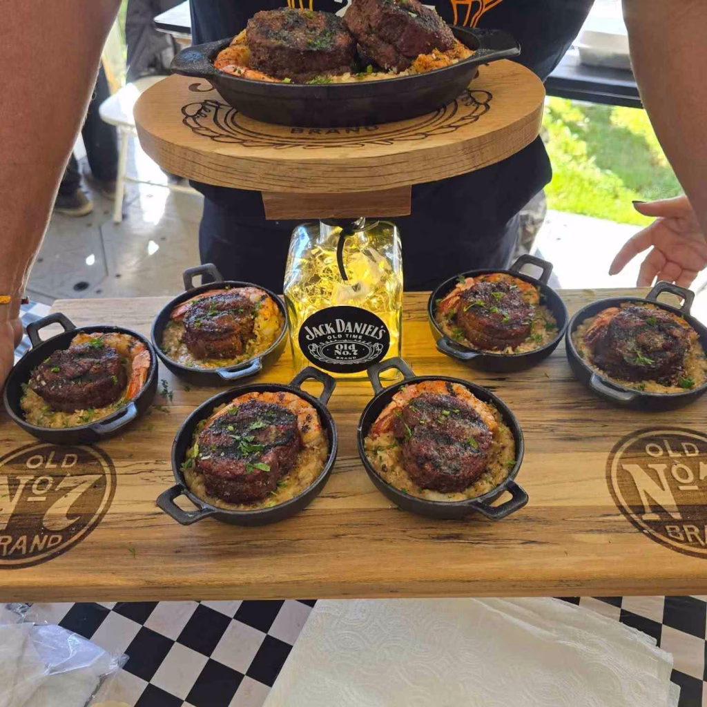 Small cast iron skillets serve perfectly cooked steaks and shrimp over rice on wooden Jack Daniel's boards, a common sight at Nashville food festivals in October.
