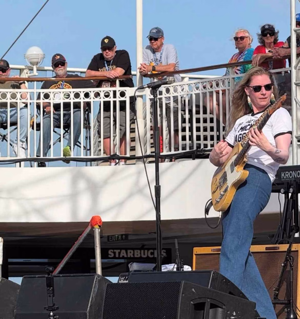 Guitarist performing energetic outdoor show on stage during Nashville in April.