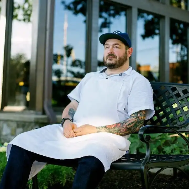 Chef Sean Brock, owner of Joyland Nashville, sits outside wearing a white chef's coat