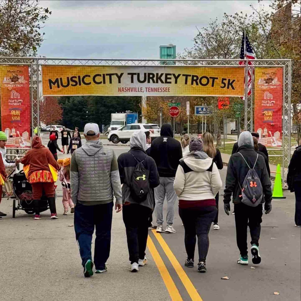 Participants walk towards the start line under the 'Music City Turkey Trot 5K' banner, a classic event in Nashville in November.