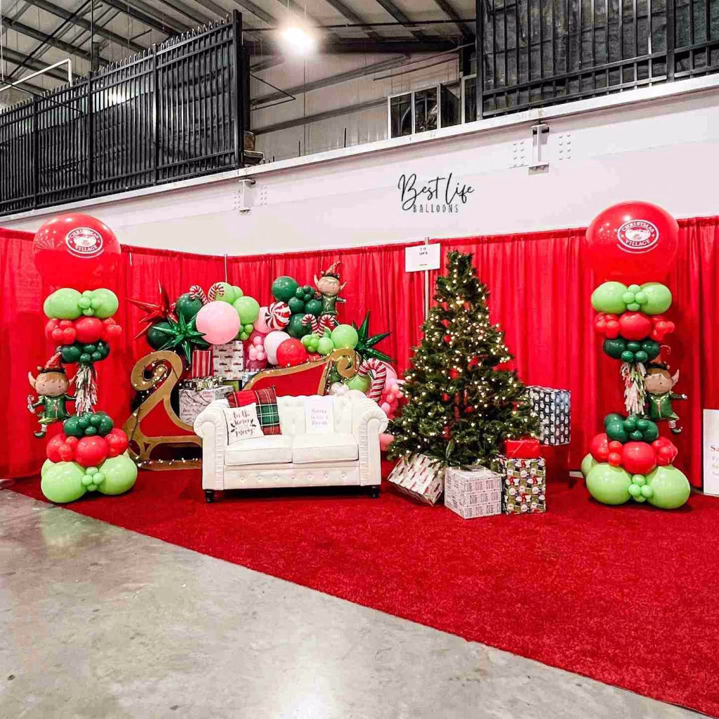 A festive Christmas display with a white couch, balloon decorations, and a Christmas tree, ready for holiday photos in Nashville in November.