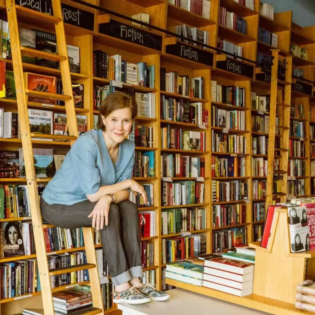 Author Ann Patchett, co-owner of Parnassus Books Nashville, sits on a rolling library ladder