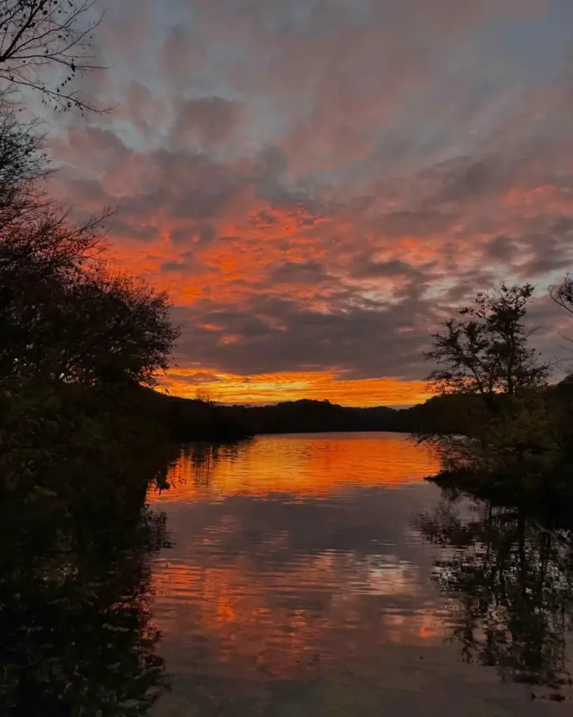 A dramatic orange and red sunset reflects over a still lake, perfect for Free Summer Activities To Do in Nashville