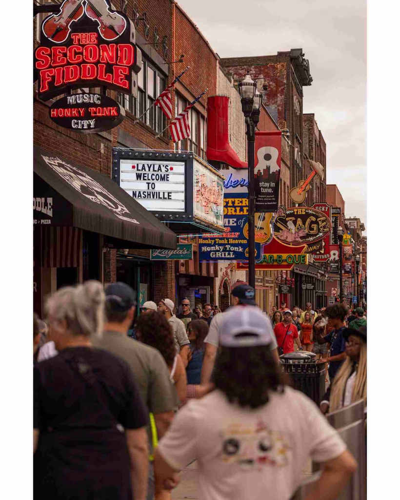 Crowded street with neon signs and shops in Nashville in June.