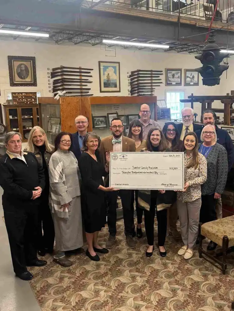 A large group holds an oversized check in a historical gallery at the Tennessee State Museum Nashville.