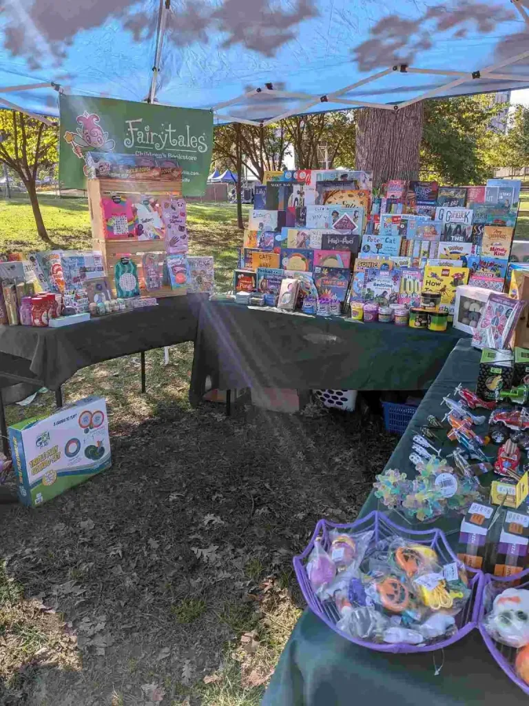An outdoor display of colorful children's books and toys, a setup by Fairytales Bookstore Nashville.