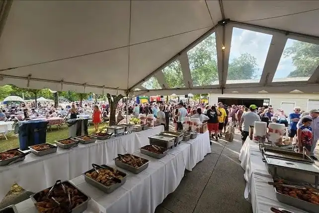 A catered buffet table under a tent at an outdoor event by Uncle Bud's Nashville
