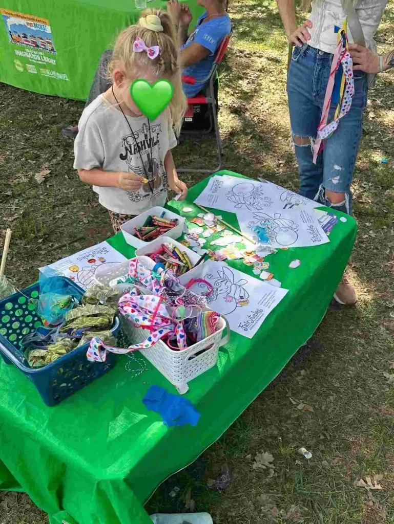 A young girl colors fairy wings at an outdoor craft table hosted by Fairytales Bookstore Nashville.