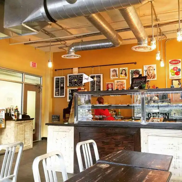 The rustic white tables and chairs inside the bright, industrial space of Yeast Nashville bakery.
