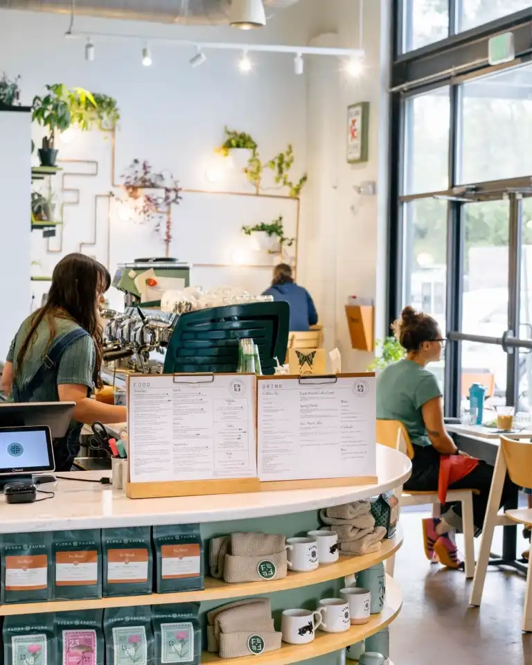 The counter area of Flora and Fauna Nashville, featuring a menu, merchandise, and coffee machine