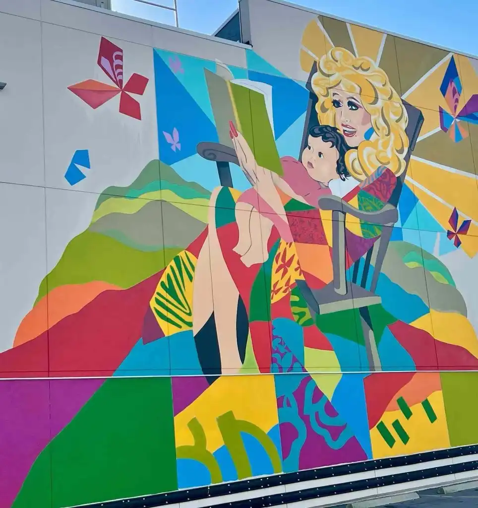 East Nashville Summer Bucket List Guide A vibrant mural of a blonde woman reading to a child, a beautiful addition to the East Nashville Summer Bucket List.