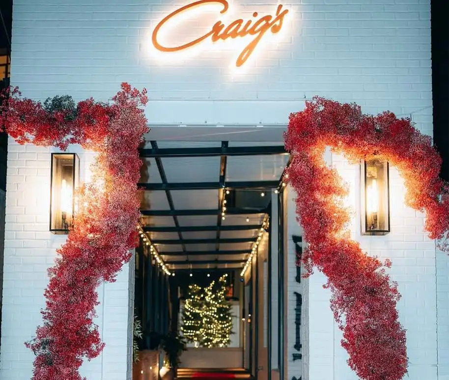 Craig's restaurant entrance with a white brick facade and red floral decor is one of the best Restaurants in Downtown Nashville. 