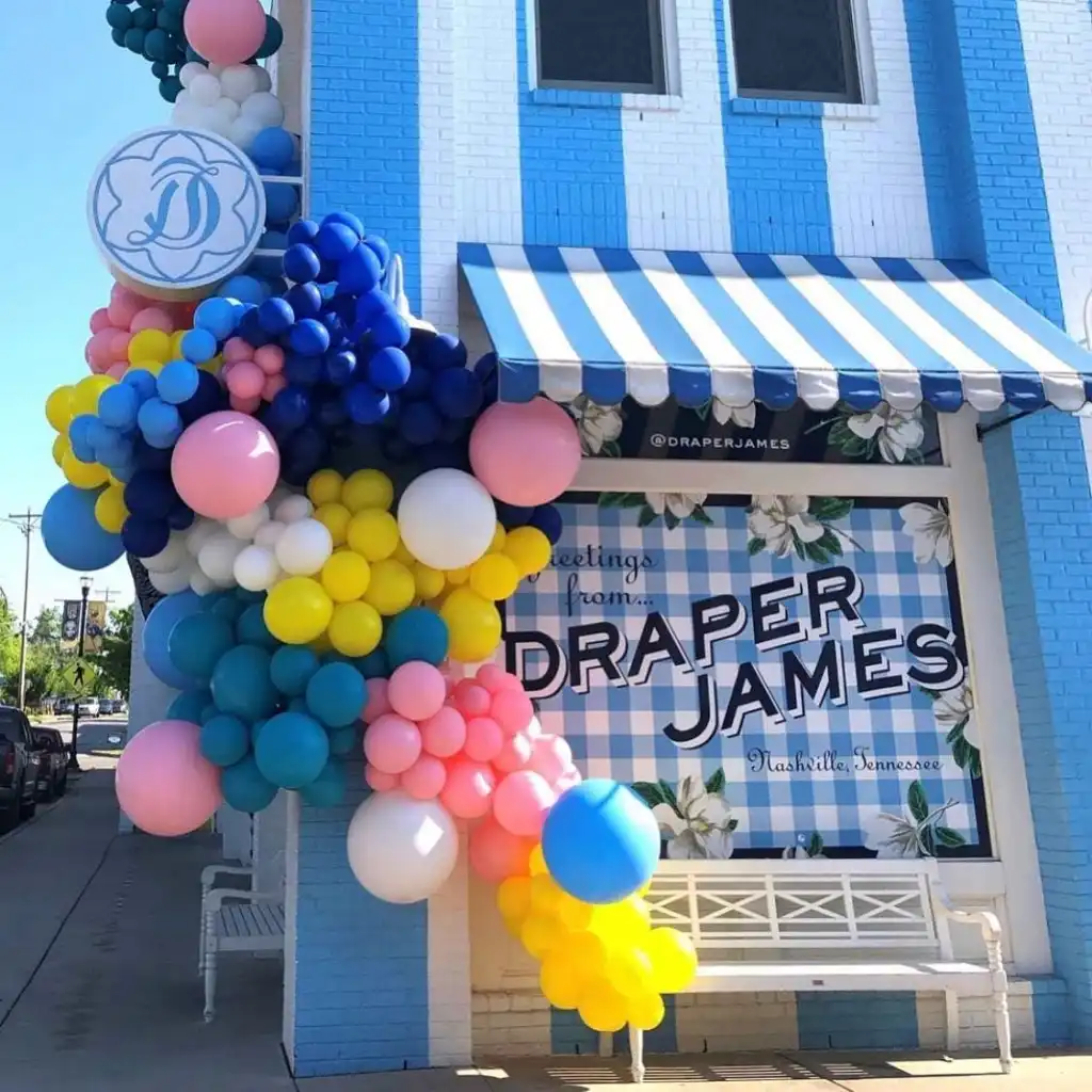 Nashville 12 South: The Complete Neighborhood Guide The bright blue and white striped exterior of Draper James is beautifully adorned with colorful balloons, a key Nashville 12 South photo spot.