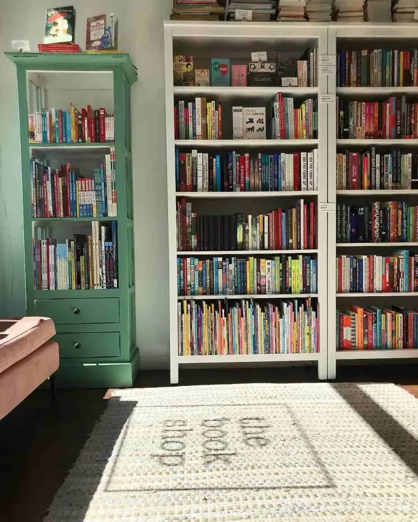 East Nashville Summer Bucket List Guide A cozy bookstore interior with colorful shelves and a rug reading "the bookshop," a delightful East Nashville Summer Bucket List stop.